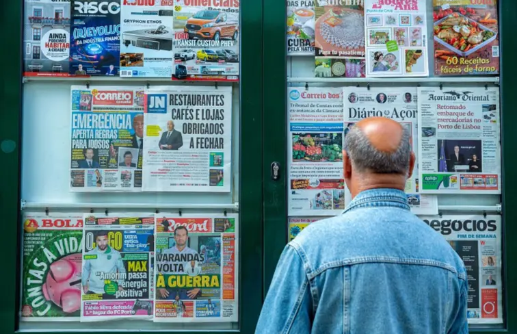 Pessoa a ver jornais expostos num quiosque